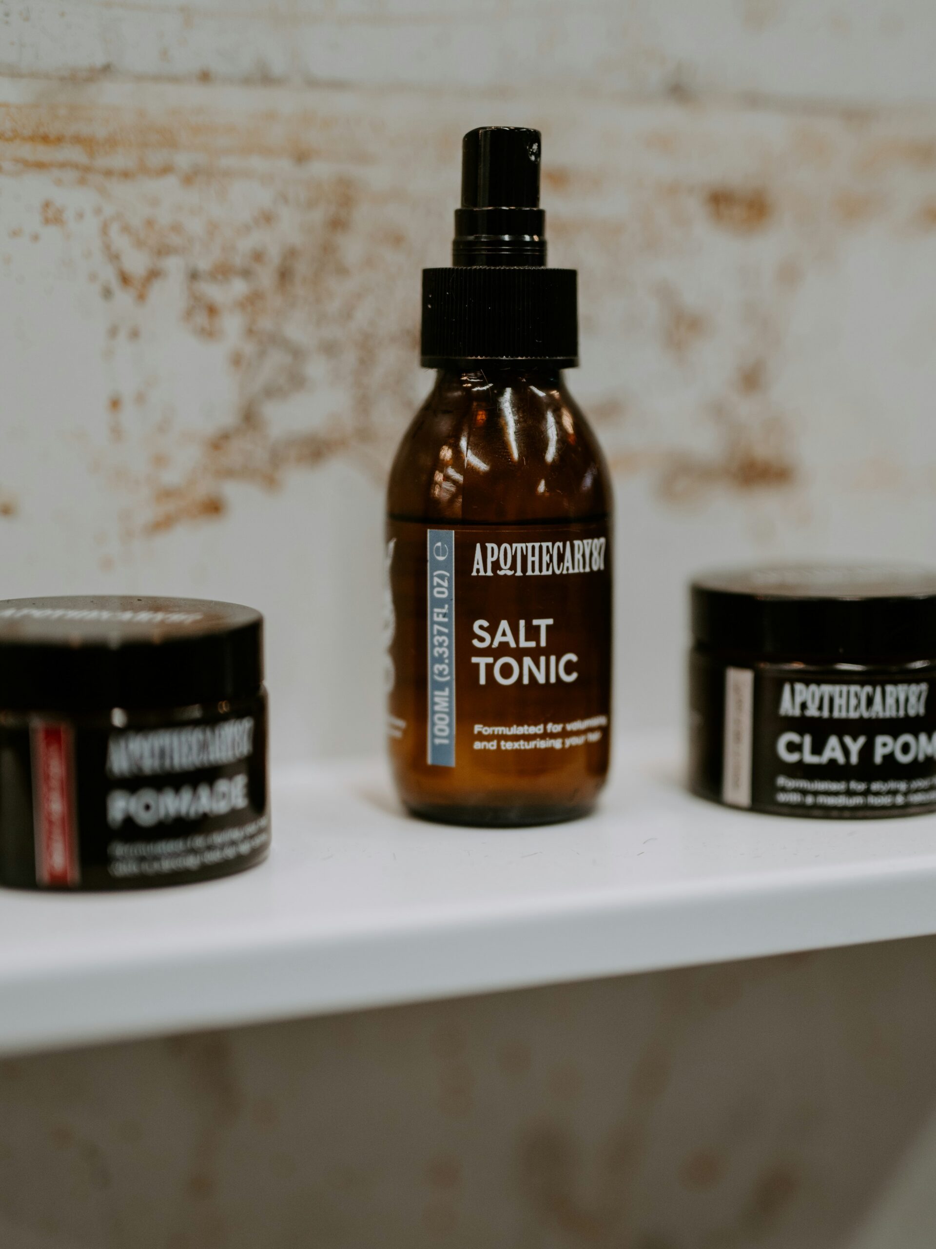 Een reeks haarstylingproducten voor mullet-kapsels in bruine verpakkingen op een witte plank.