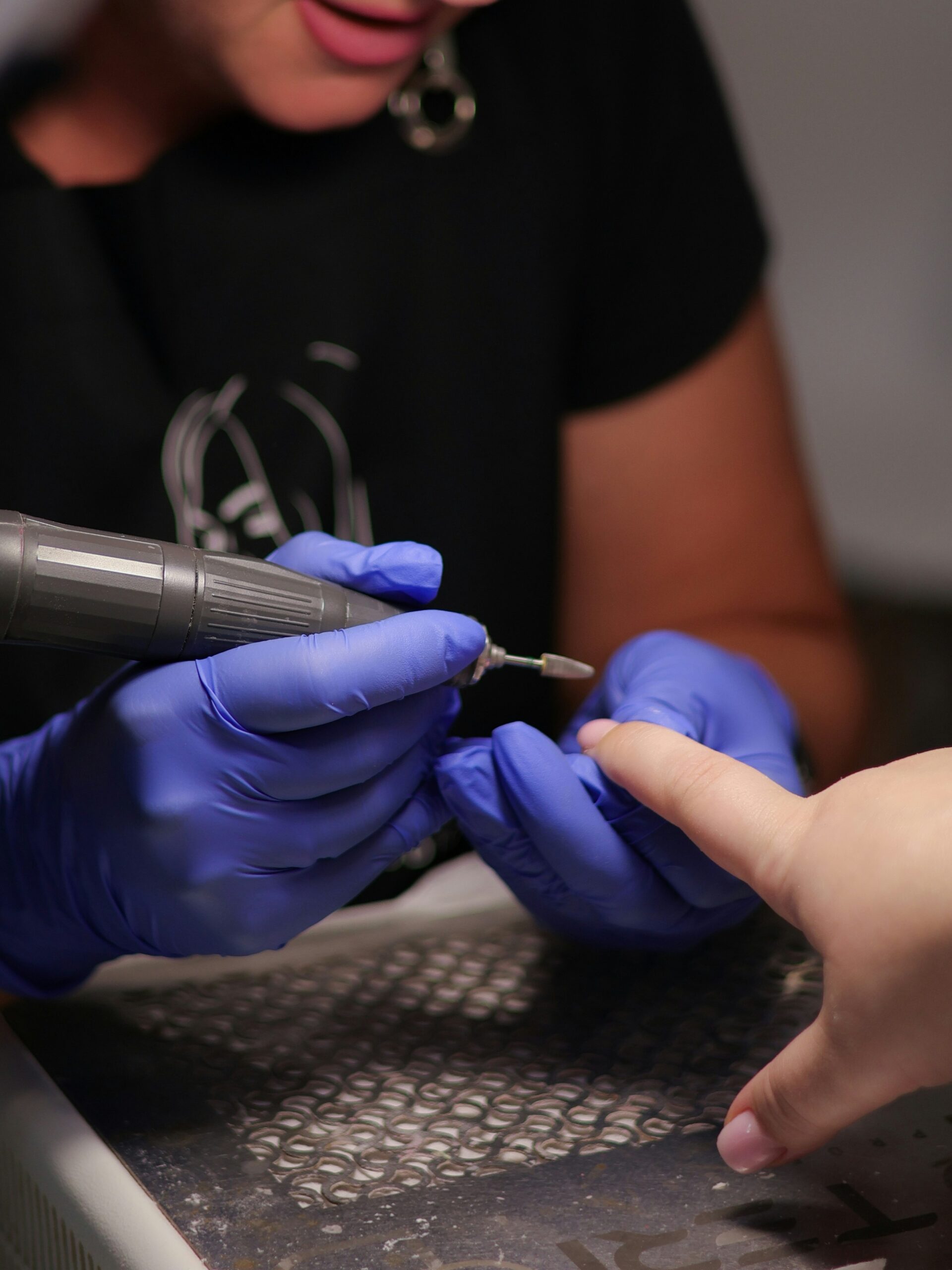 Nagelstyliste die met een nagelfrees BIAB verwijdert in de salon