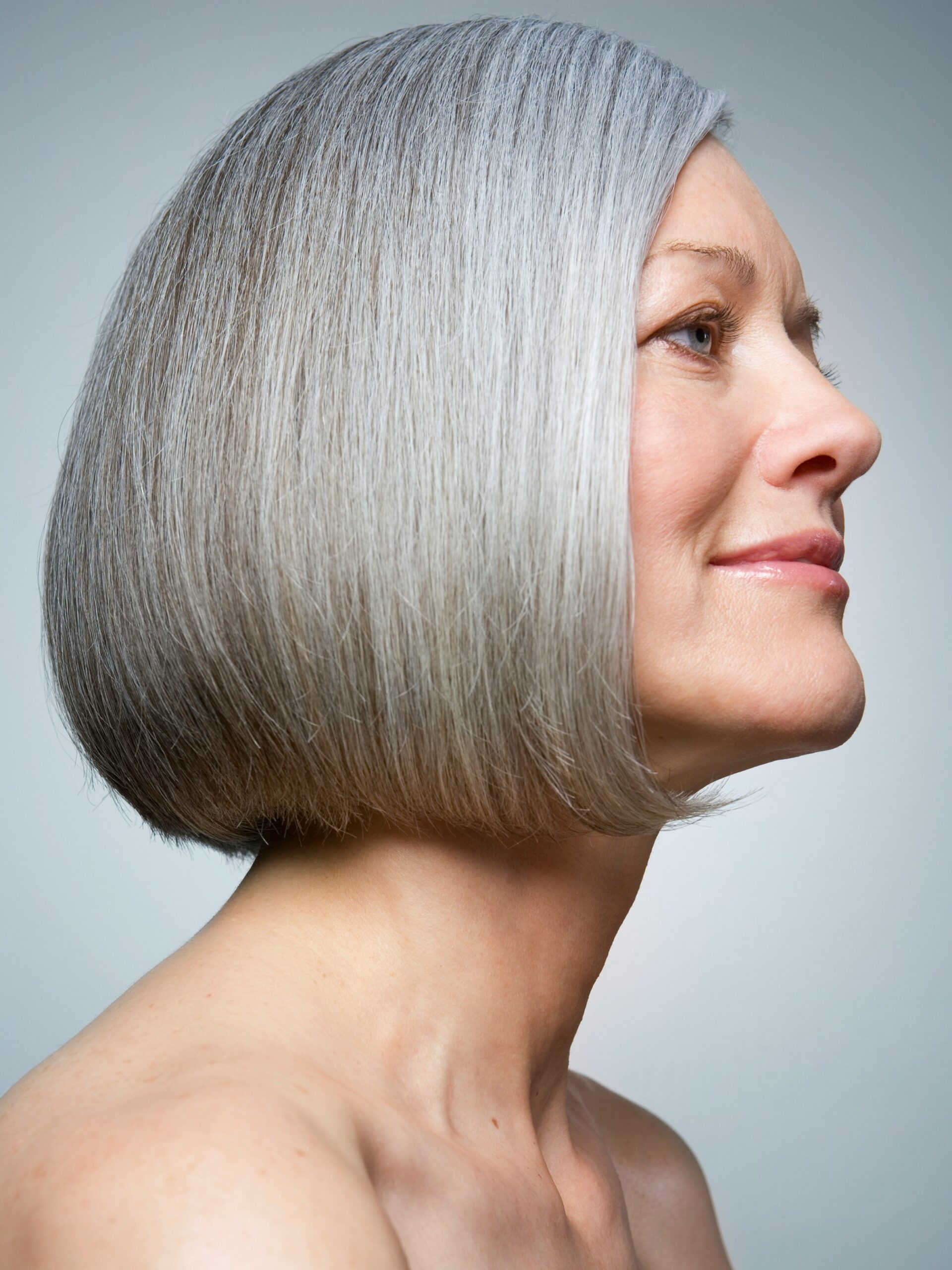 Portret van een vrouw met een gezonde en glanzende grijze bob, van opzij gefotografeerd