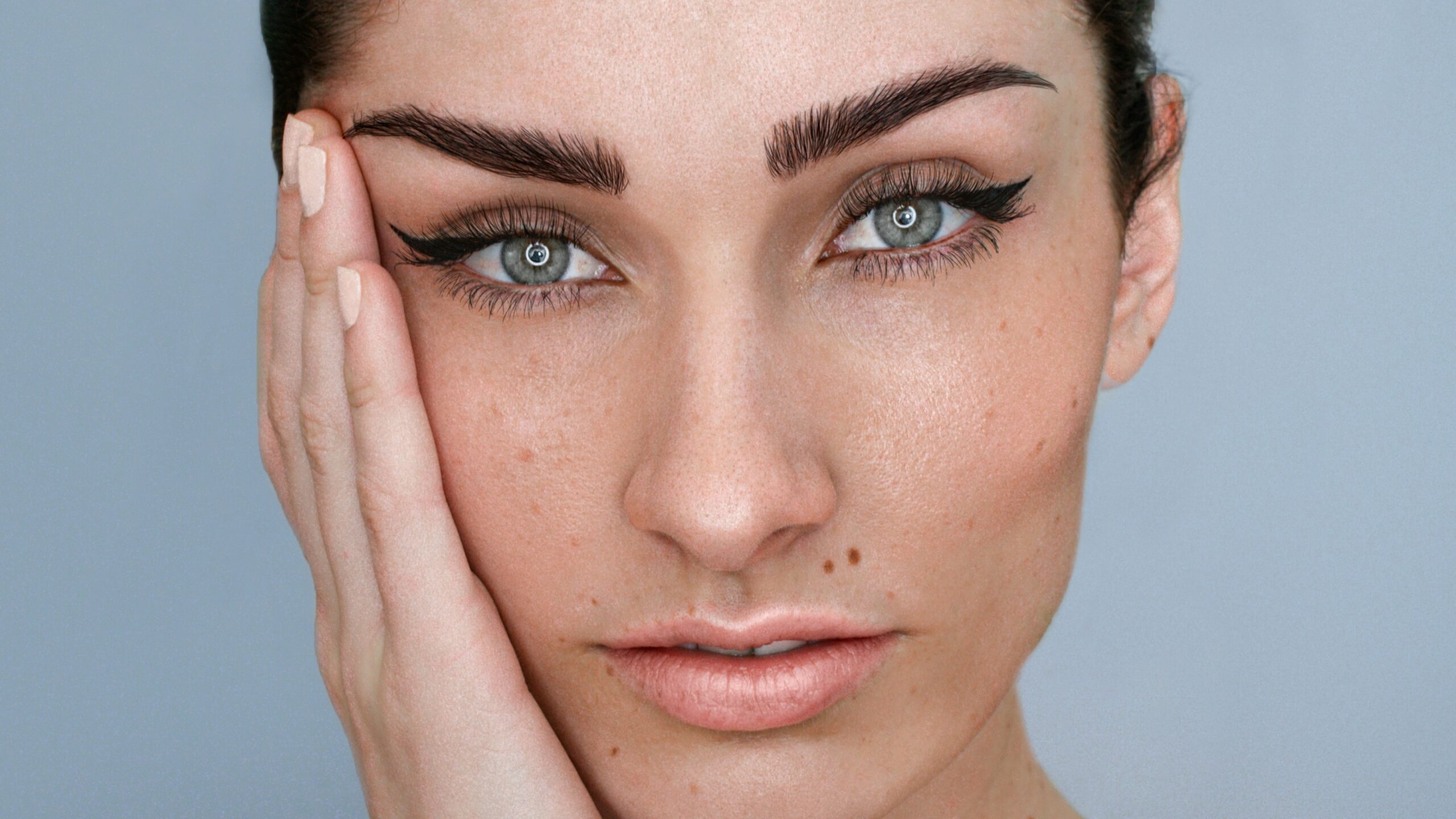 Close-up van het gezicht van een vrouw met microblading op haar wenkbrauwen en natuurlijke make-up, met donker haar dat is opgestoken