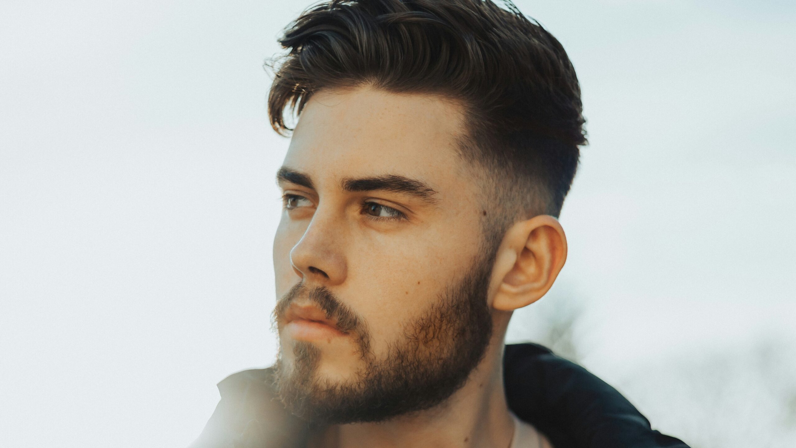 Man die buiten staat met donker haar en een taper fade kapsel met een getextureerde bovenkant
