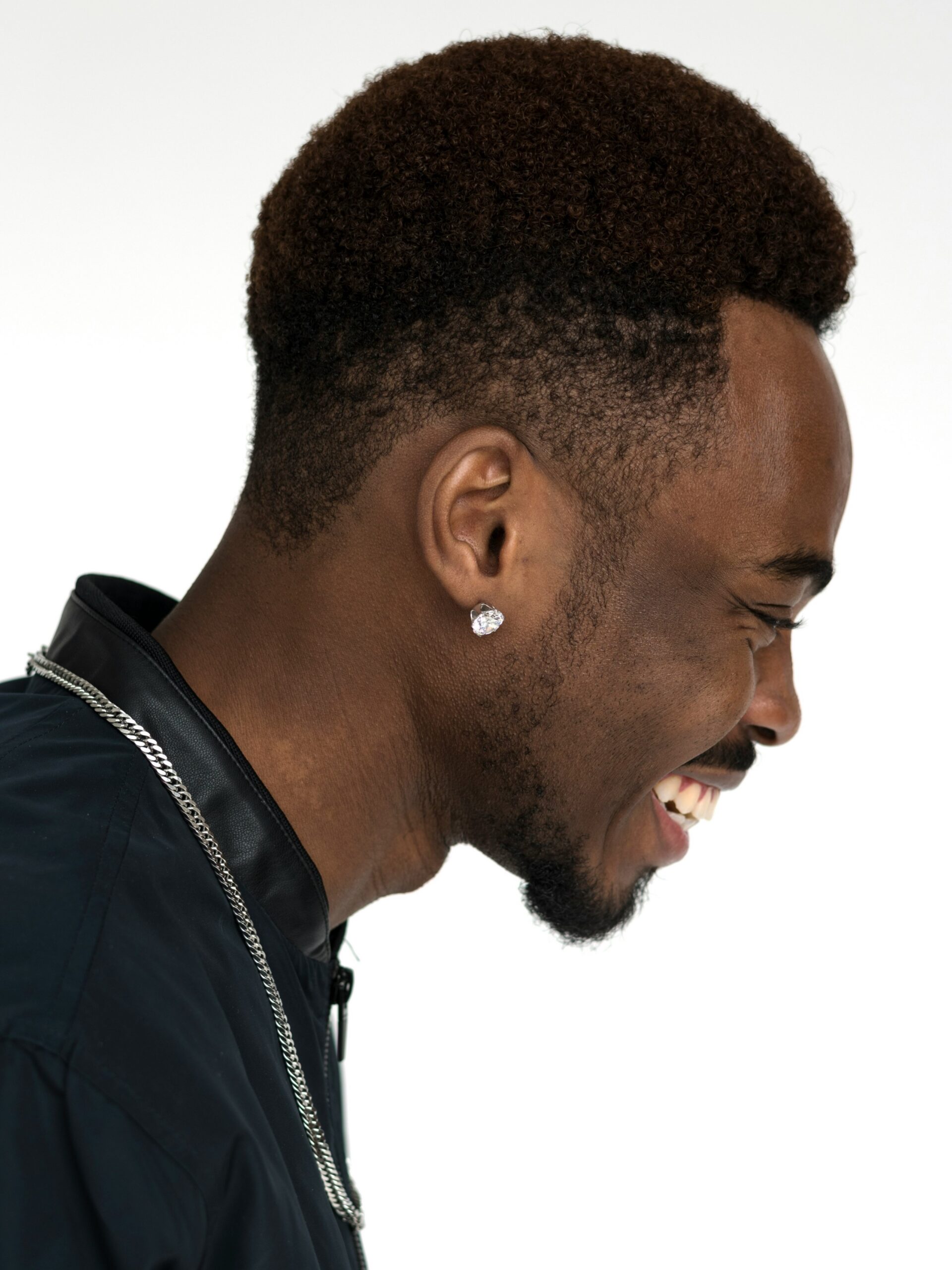 Zijaanzicht van een lachende man met afrohaar gecombineerd met een high taper fade kapsel