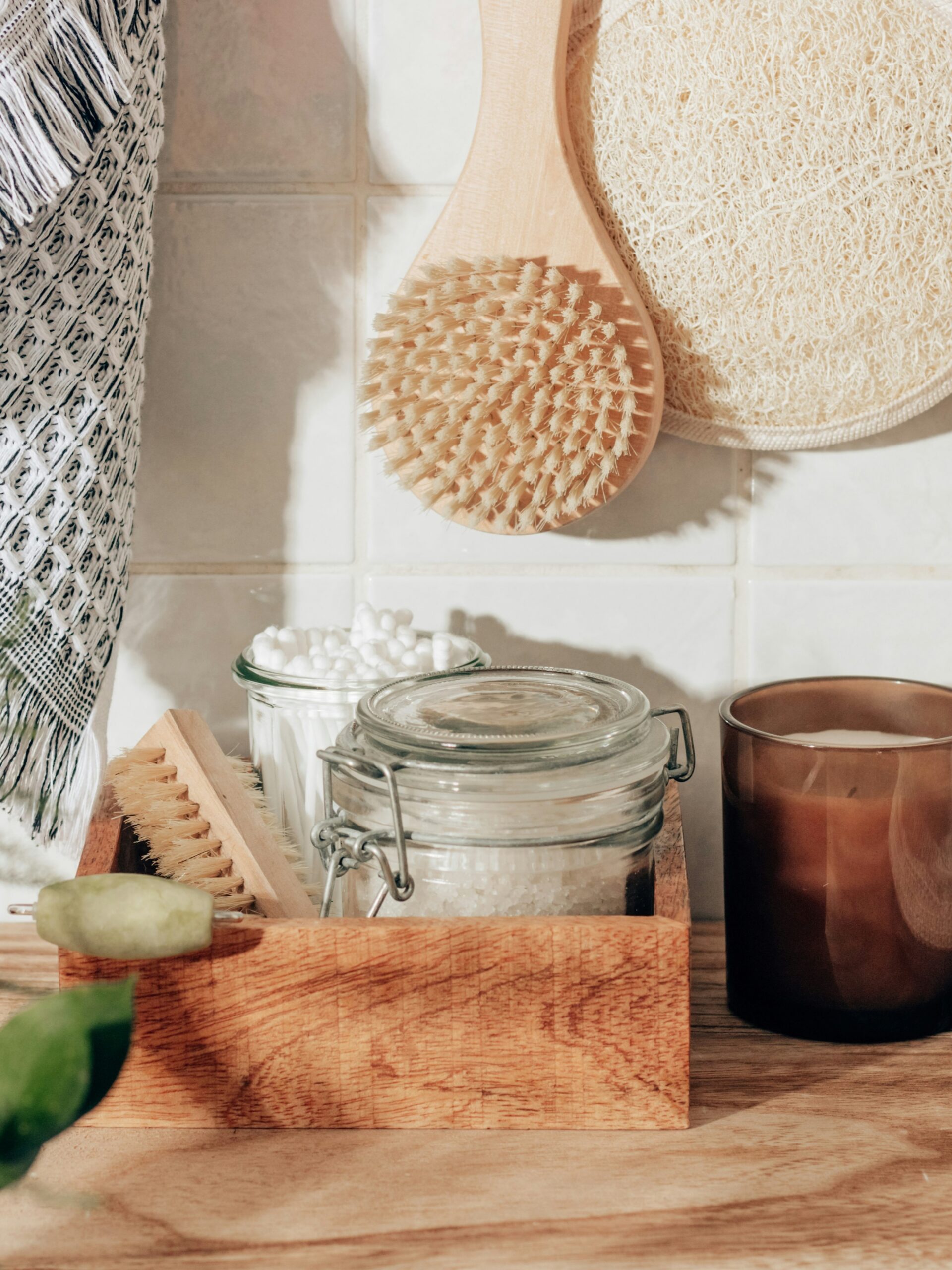 Gestylede foto van badkameraccessoires, waaronder een scrubhandschoen, lichaamsborstel, badzout, wattenstaafjes en een kaars