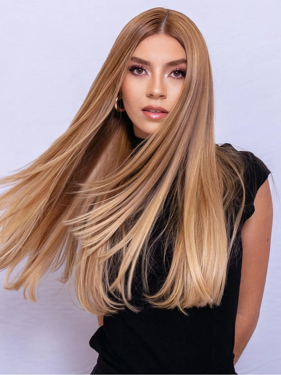 Studioportret van een vrouw die haar lange, glanzende karamelblonde haar naar achteren zwiept