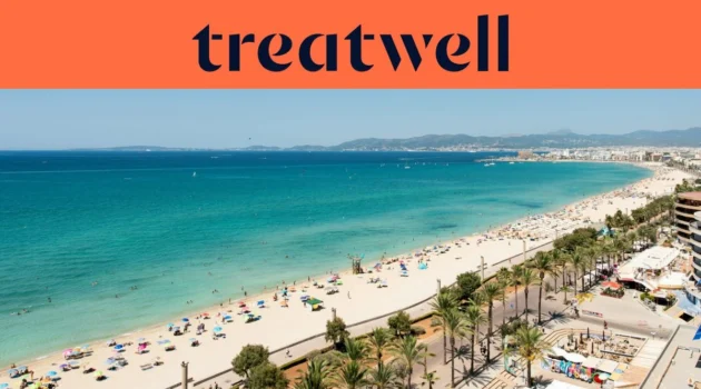 Een luchtfoto van Playa de Palma op Mallorca, met een lange boog van goudkleurig zand, rijen parasols, kalm turquoise water en een met palmen omzoomde boulevard langs de stad, met heuvels in de verte onder een strakblauwe lucht.