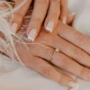 Klassieke witte French manicure op natuurlijke, vierkant gevijlde nagels op een witte stof
