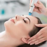 Close-up van een ontspannen vrouw met gesloten ogen tijdens een HydraFacial-behandeling in een rustige salon