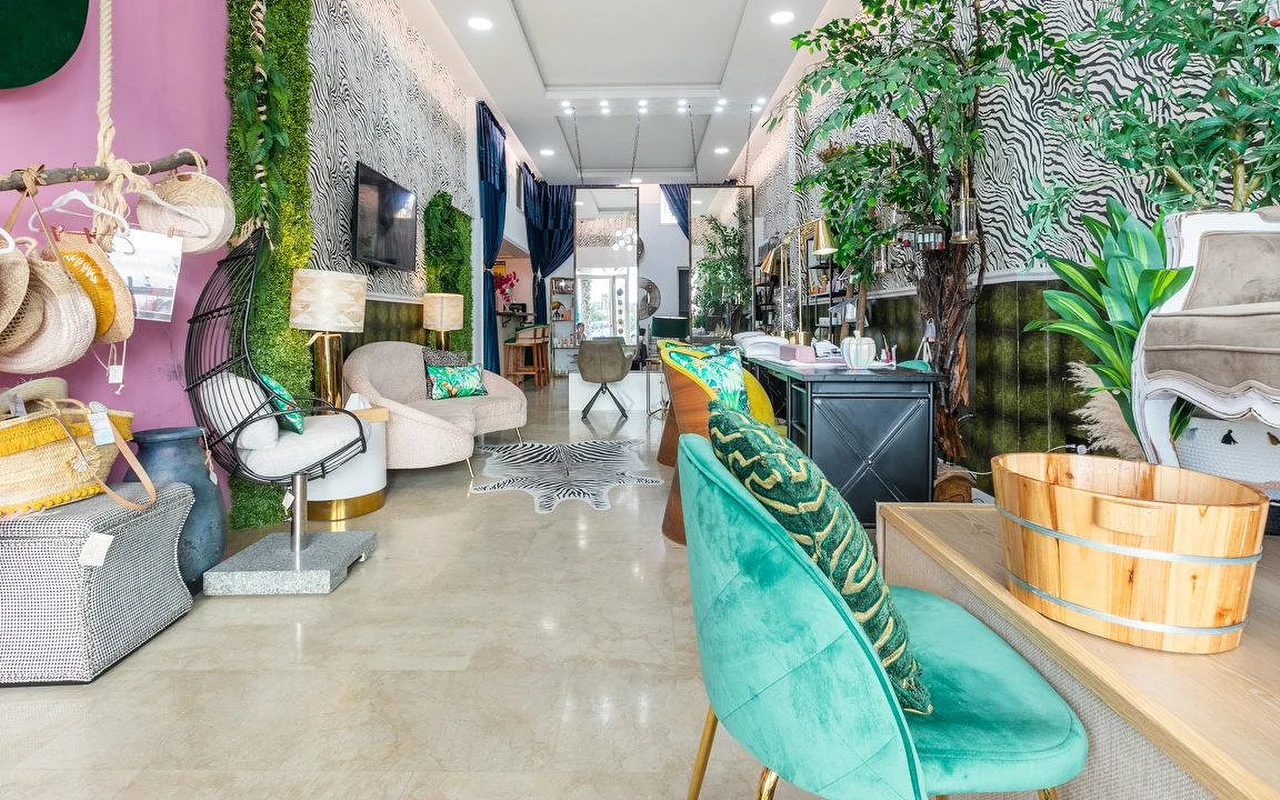 Het interieur van Brazilian Beauty Marbella, een lichte salon met zebraprint-muren, een groene plantenwand, turquoise fluwelen stoelen en een houten pedicurebak.