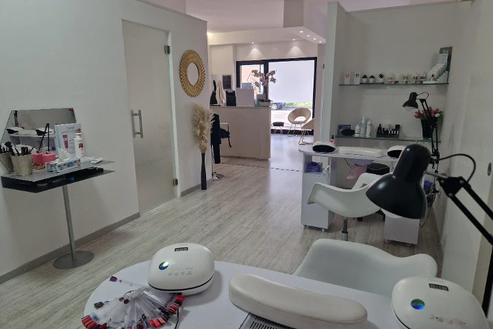 Receptie en manicurehoek bij Estetica Francesca in Olbia met een ronde muurspiegel en glazen schappen met beautyproducten.