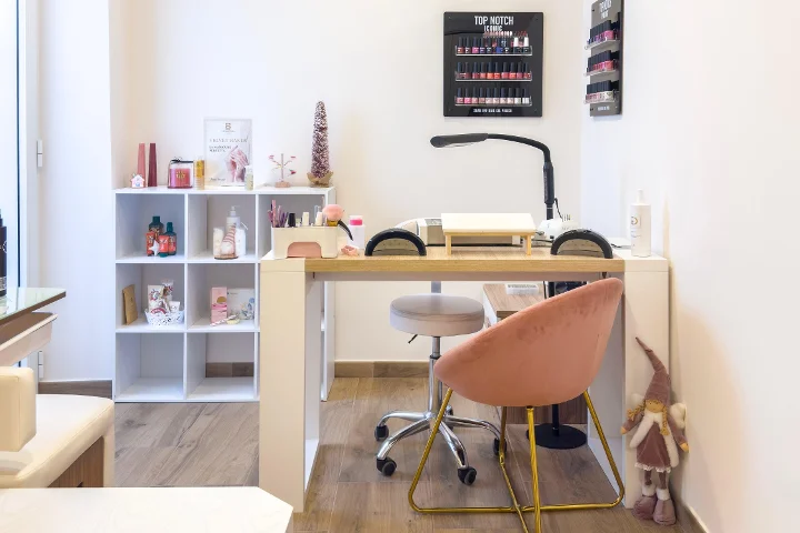 Manicurestation bij Gd Beauty Clinc di Giulia Delogu in Alghero met een roze fluwelen stoel en Top Notch-lakdisplay.
