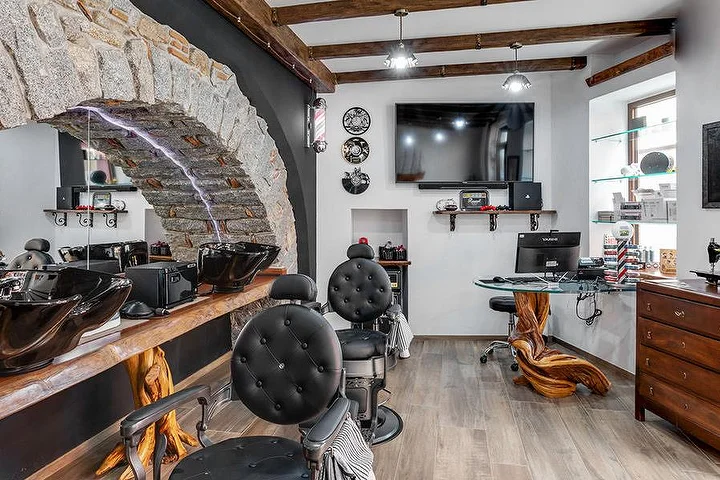 Rustieke barberstoel tegen een stenen boogwand bij La Bottega di Pablo in het bergstadje Lanusei.