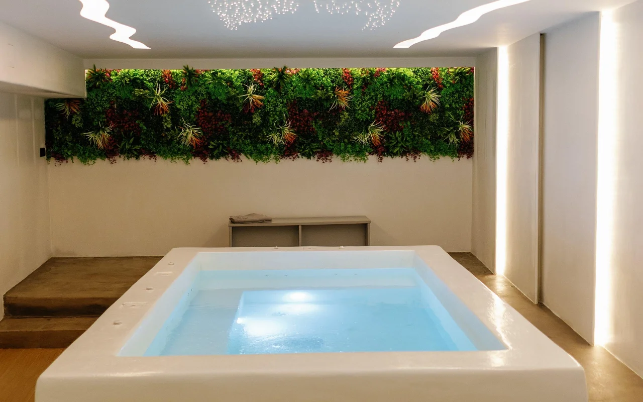 Het hydrotherapiebad van Liana Spa Therapy op Naxos, zacht van binnenuit verlicht, onder een kleurrijke groene wand van geconserveerde planten en een plafond bezaaid met piepkleine sterrenlichtjes.