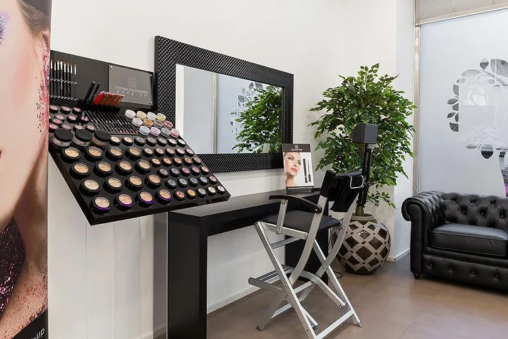 Lichte manicuresalon Top Estetica in Villanova, Cagliari, met turquoise muur, bloemige bureaus en marmeren vloeren.