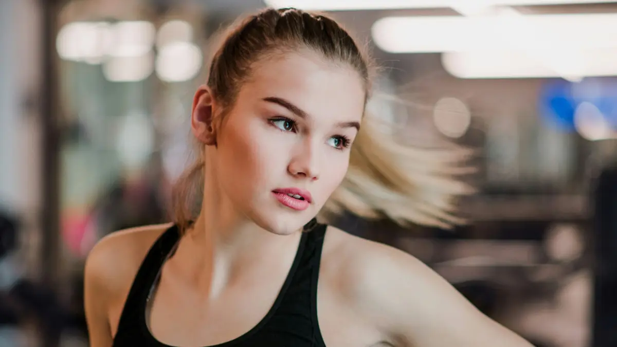 Een jonge vrouw in een sporttopje beweegt zijwaarts terwijl haar staart naar de zijkant zwiept
