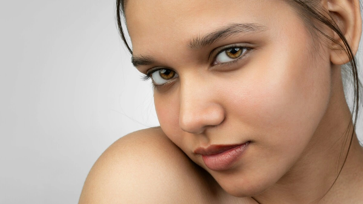 Close-up van een vrouw die naar de camera lacht en haar gladde, make-uploze huid laat zien